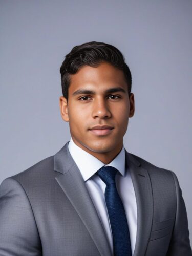 Headshot of a young Indigenous Australian man in a grey suit